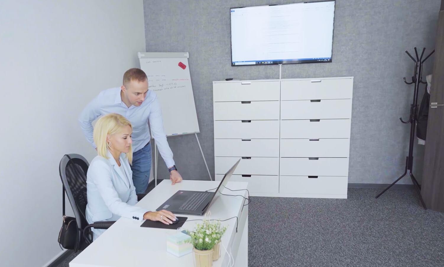 Mężczyzna i kobieta w biurze patrzą na ekran laptopa